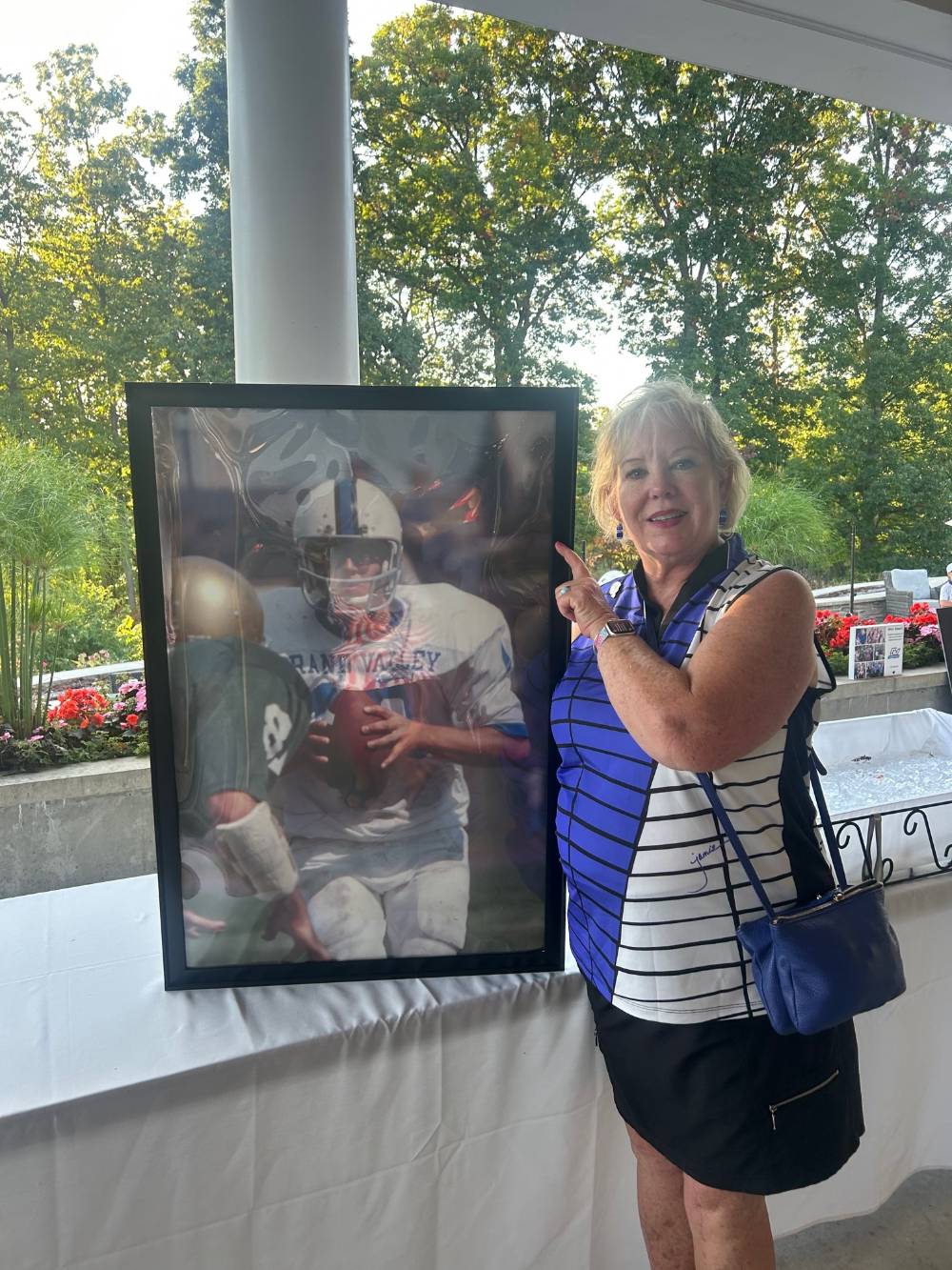 An alum holding a photo of a GVSU Football player.